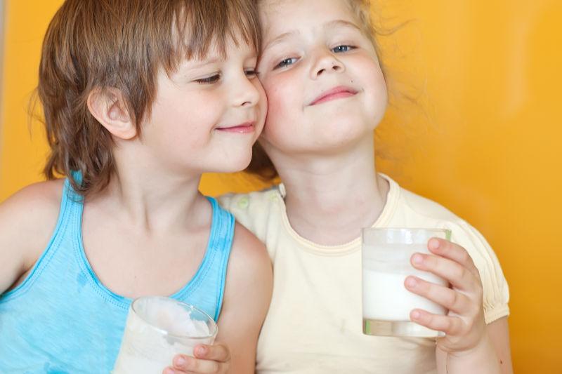 黄色背景下快乐的孩子们喝牛奶