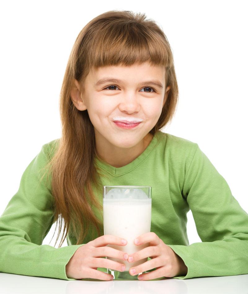 白色背景下可爱的小女孩拿着一杯牛奶