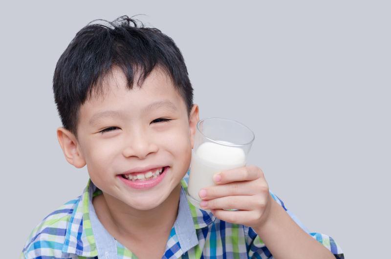 微笑的孩子捧着一杯牛奶