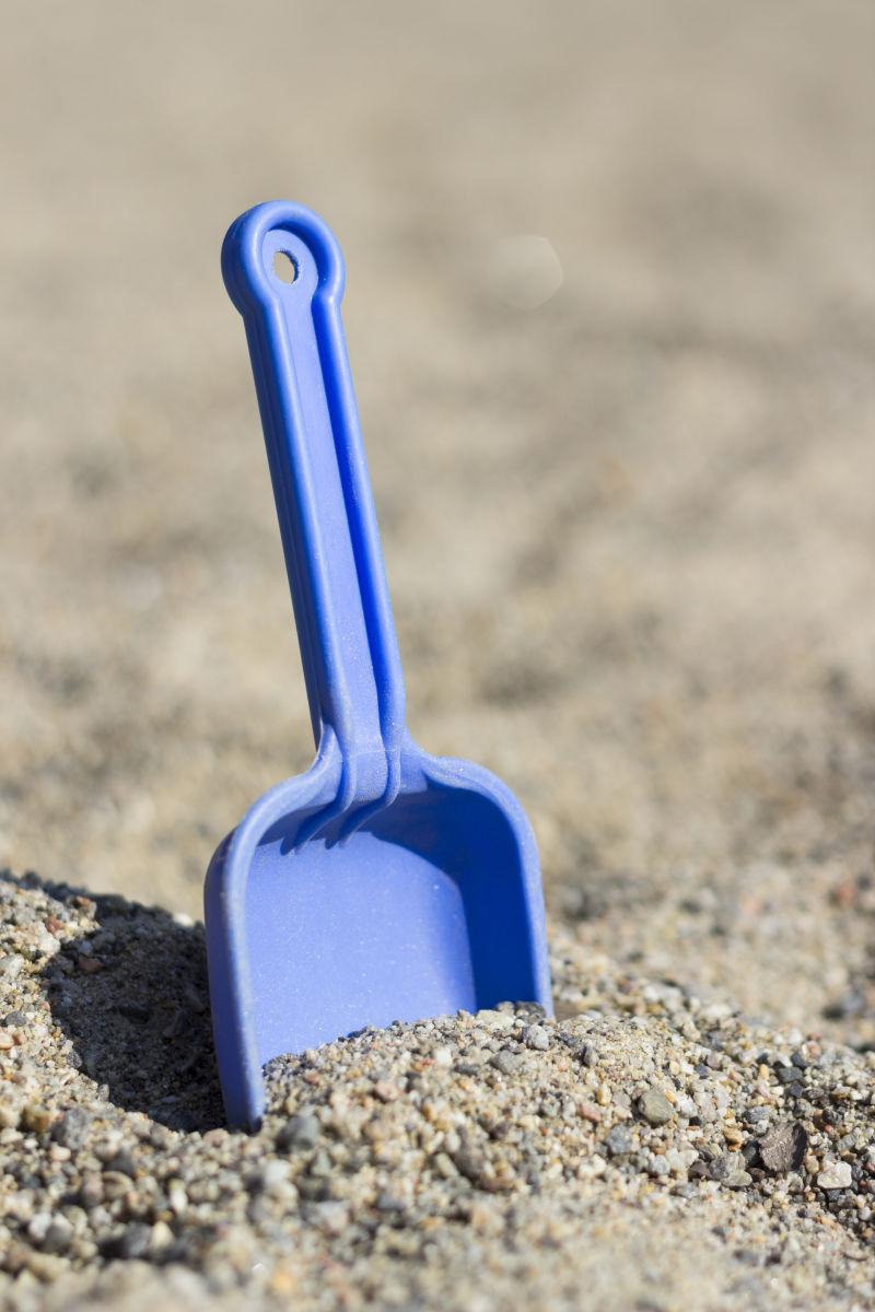 插在沙子里的蓝色塑料铲子