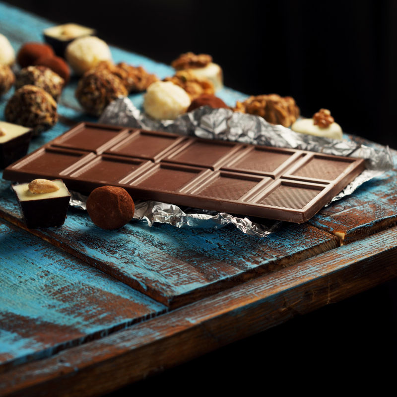 旧木桌上的黑巧克力和各种巧克力糖果