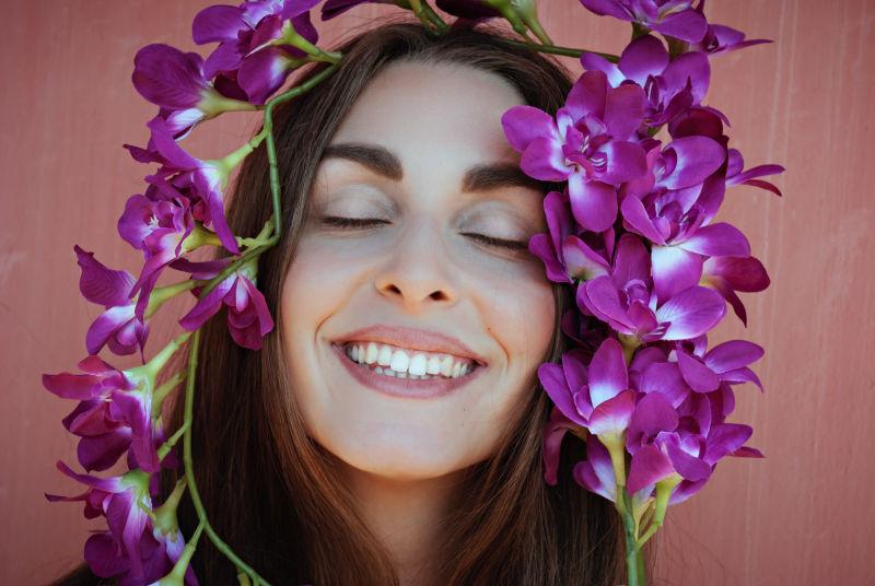 紫色兰花包围的美丽微笑的女孩