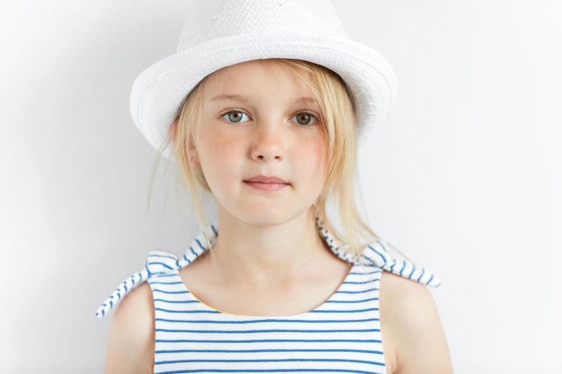 穿着条纹装带着白色帽子的金发小女孩