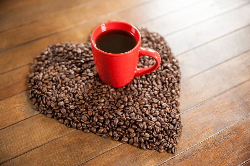 木制咖啡桌上有心形咖啡豆和红色咖啡杯