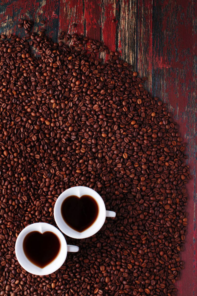 木桌上的两杯爱心咖啡和咖啡豆