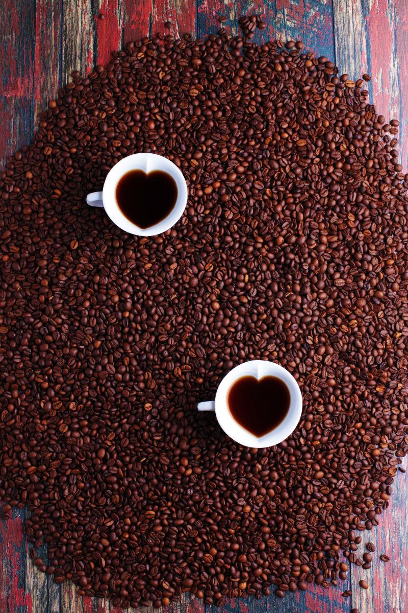 木桌上的咖啡豆和两杯爱心咖啡