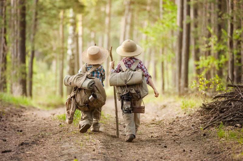 两个男孩带着背包徒步行走在森林路