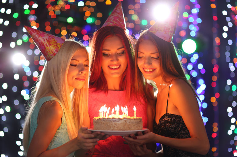 三个女孩拿着生日蛋糕