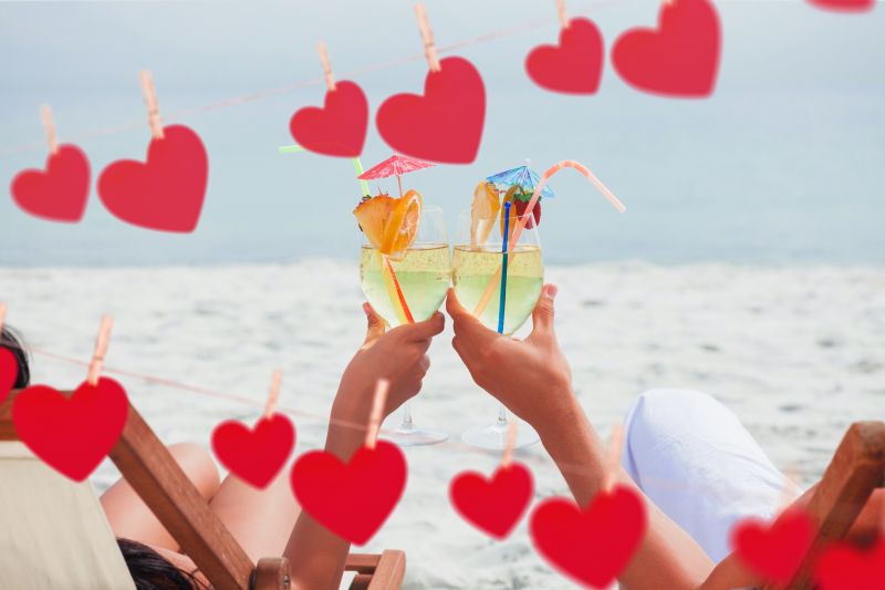在沙滩上喝饮料对杯的情侣