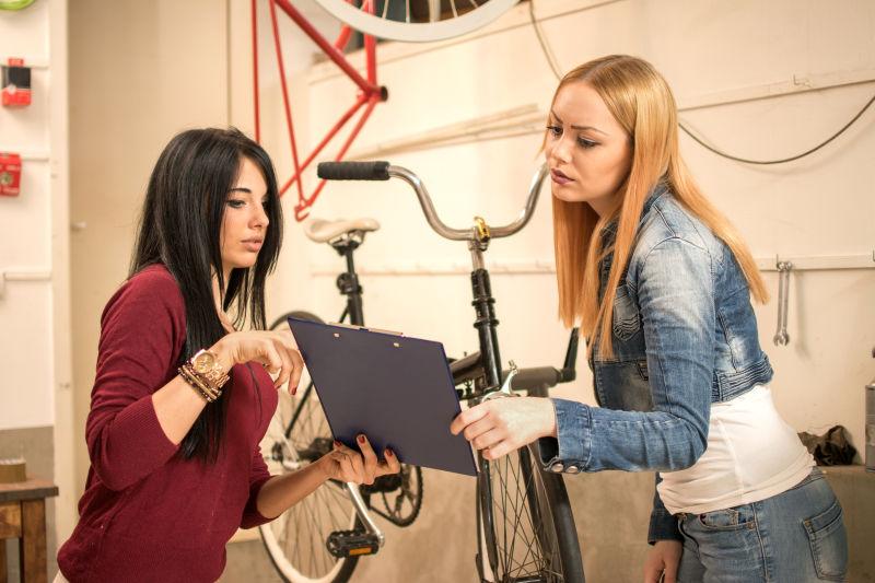 两个年轻的女朋友在自行车修理店做文书工作
