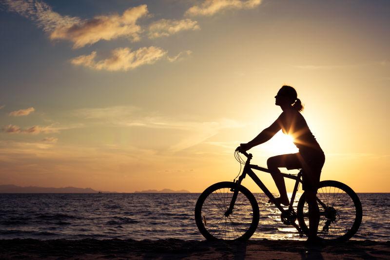 在海滩上的快乐女人骑着自行车
