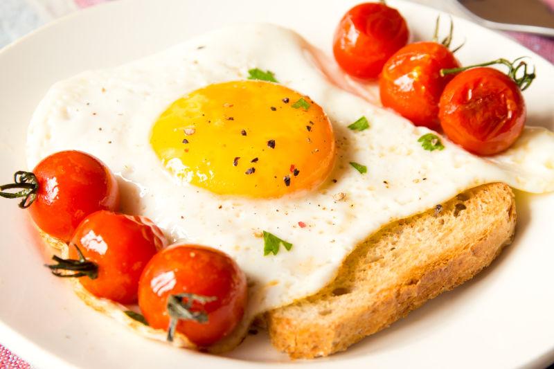 白色餐盘里美味的面包鸡蛋和小番茄
