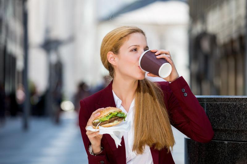 年轻的商务女性在城市街道上吃午餐