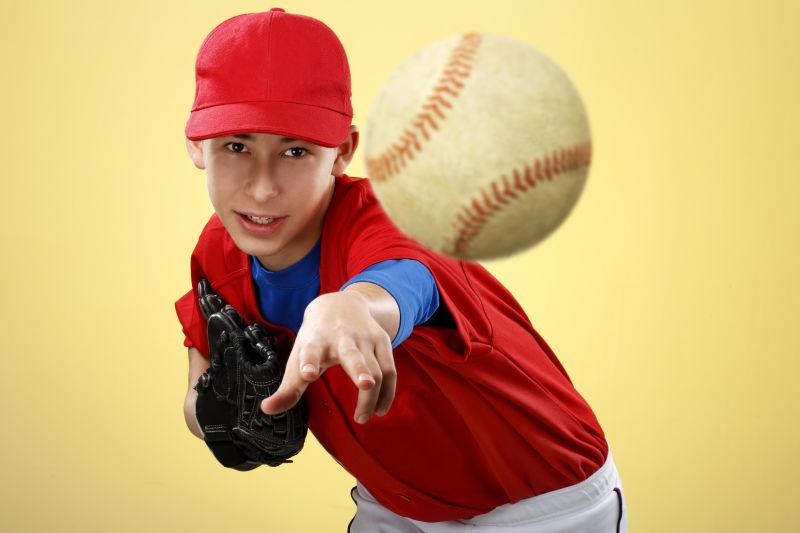 彩色背景下一位漂亮的棒球运动员在投球