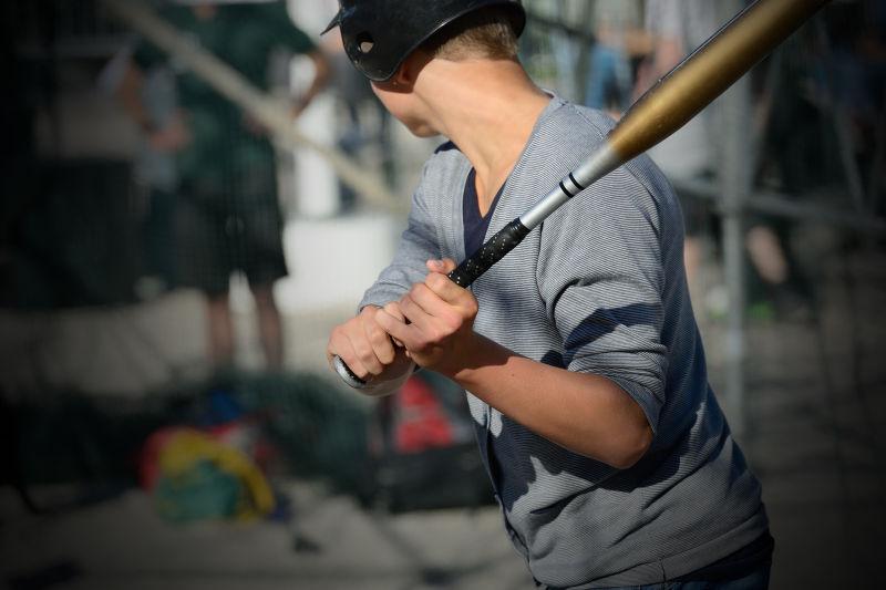 男孩摆动蝙蝠打棒球