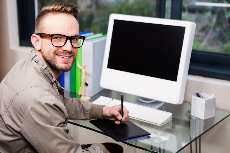 坐在台式电脑前工作的微笑的男设计师