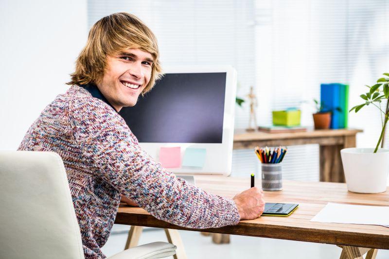 坐在办公桌前使用平板电脑工作的年轻男性设计师