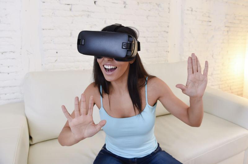 坐在沙发上带着VR眼镜兴奋的女人
