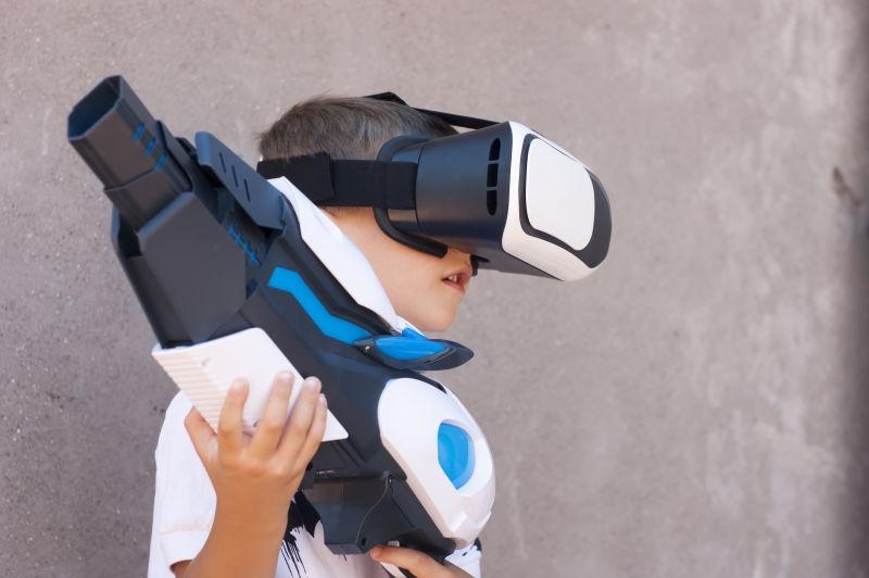 带着VR眼镜拿着枪玩游戏的男孩