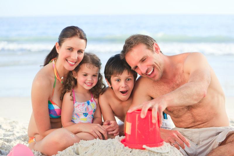 在海滩上玩沙子的幸福一家人