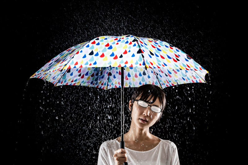黑背景下雨天打雨伞的女性