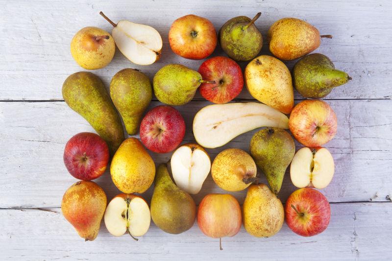  白色桌上的不同品种和颜色的苹果和梨子