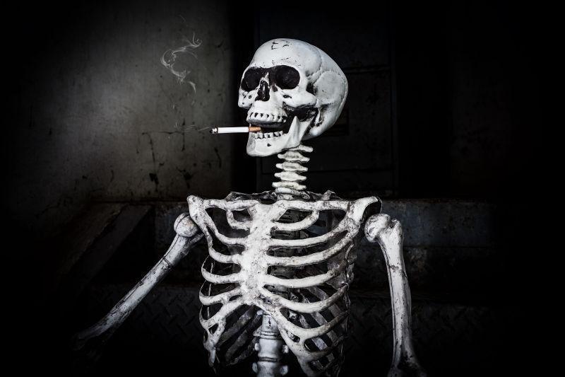 黑色背景下吸烟的骨架寓意请戒烟或停止吸烟以保持健康