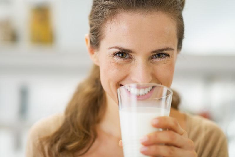 微笑的年轻女子喝牛奶