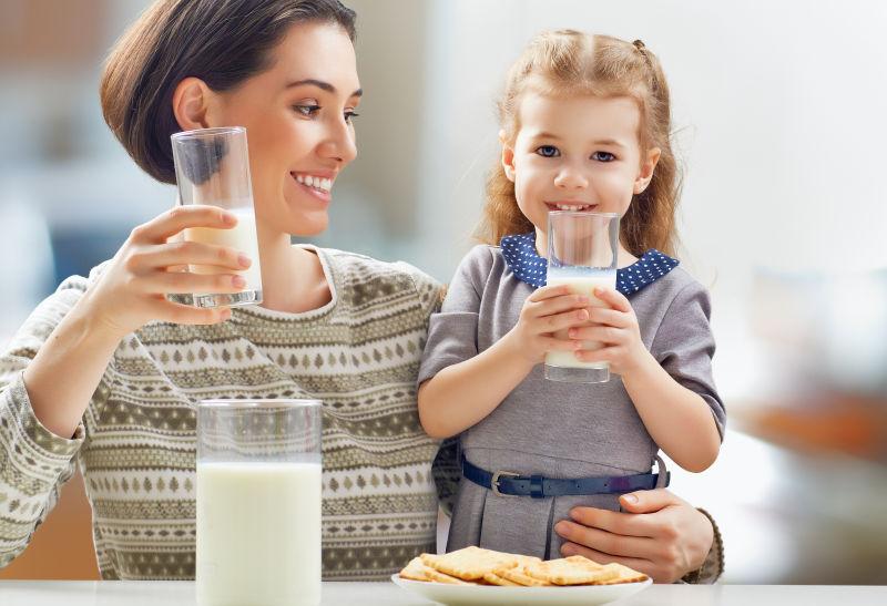 在厨房喝牛奶的母亲和女孩