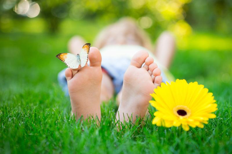 春天公园里孩子脚上的蝴蝶和黄色的花