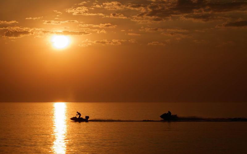 日落时分人们在海面上玩摩托艇