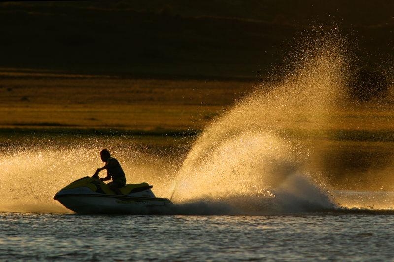 日落时分的海面上男子乘摩托艇