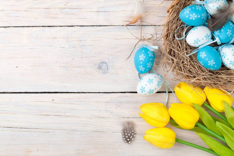 木桌上的复活节彩蛋和黄色郁金香