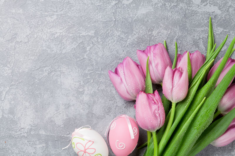 粉红郁金香花和复活节彩蛋在石桌上