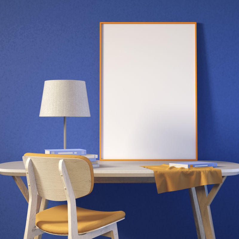蓝色墙壁旁的书桌和空白画框