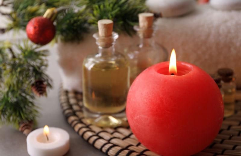 木桌上的红色球形蜡烛和玻璃瓶装的护肤品