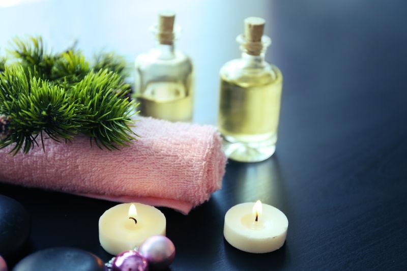 灰色桌上的毛巾蜡烛和玻璃瓶装护肤品