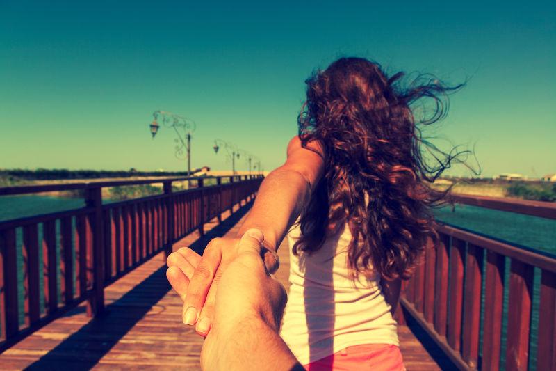 海滩桥上女子拉着男友的手