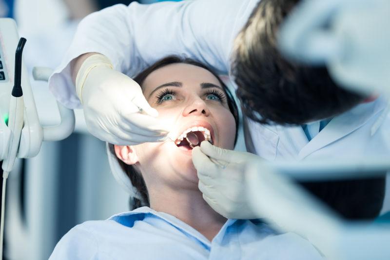 年轻女人正在被医生检查牙齿
