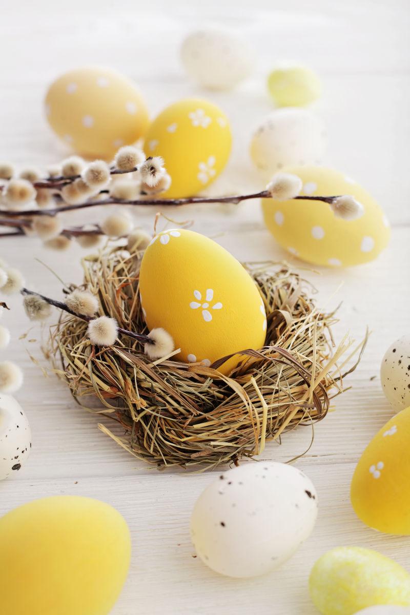 白色桌上的黄色复活节彩蛋和鸡窝