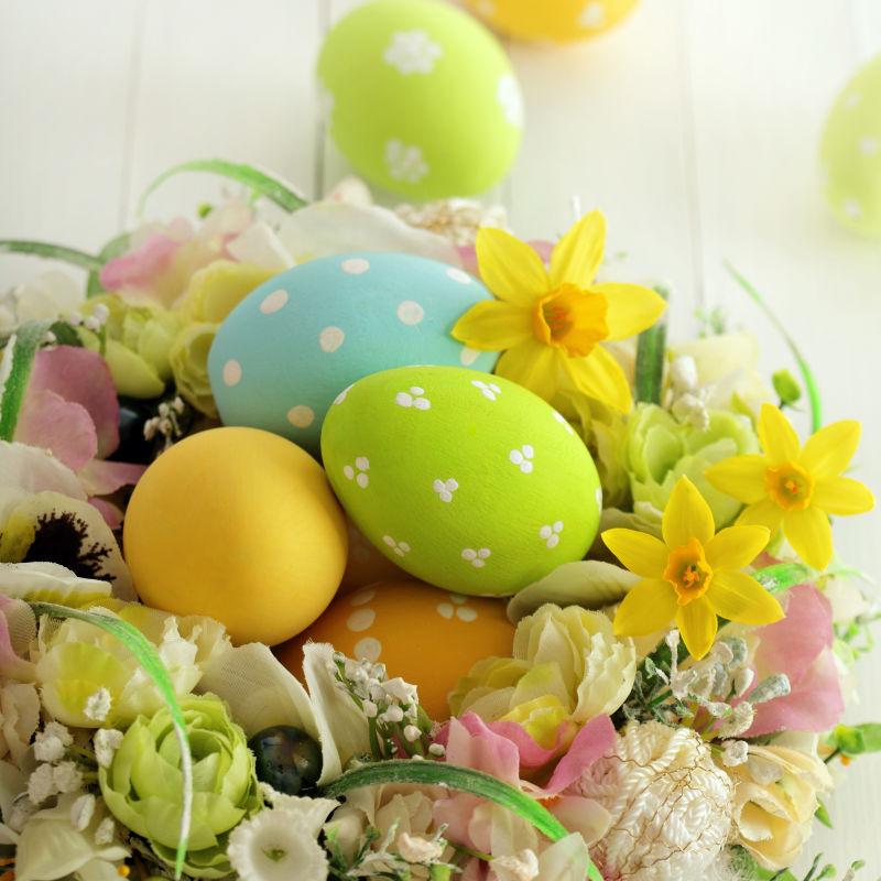 白色桌上一堆花朵里的复活节彩蛋