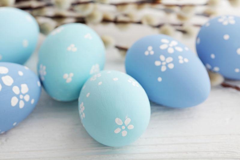 白色桌上的蓝色的画着白色花朵的复活节彩蛋