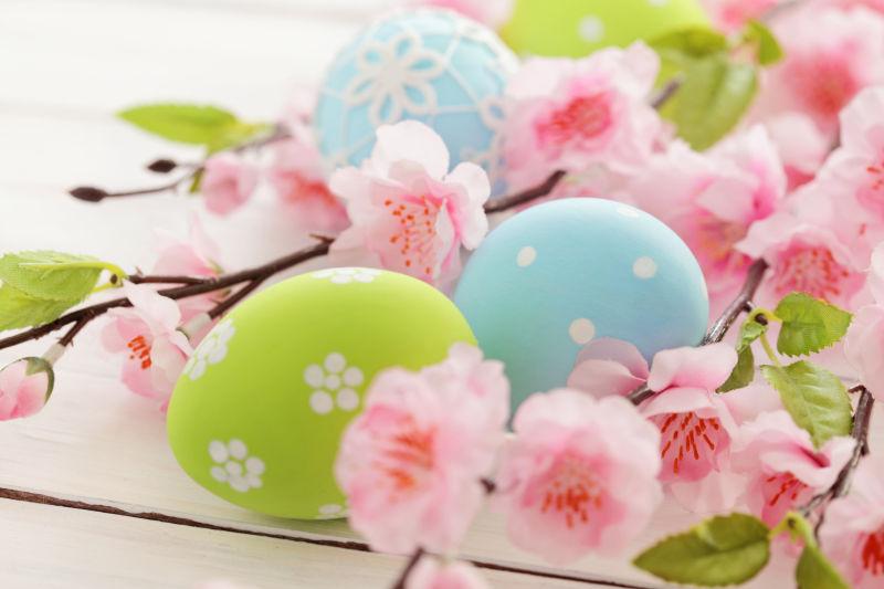 白色桌上的复活节彩蛋和粉红色的桃花花朵