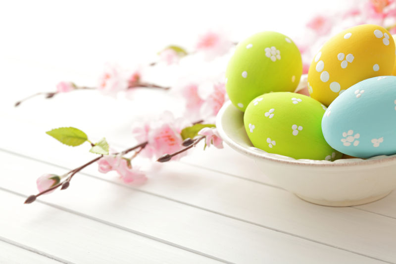 白色盘子里的复活节彩蛋和桌上的粉色花朵