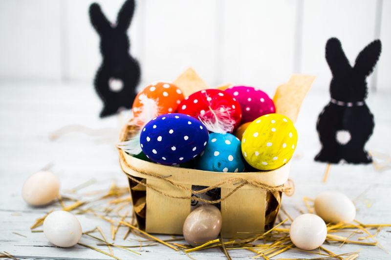 白色桌上木筐里的复活节彩蛋和兔子剪纸