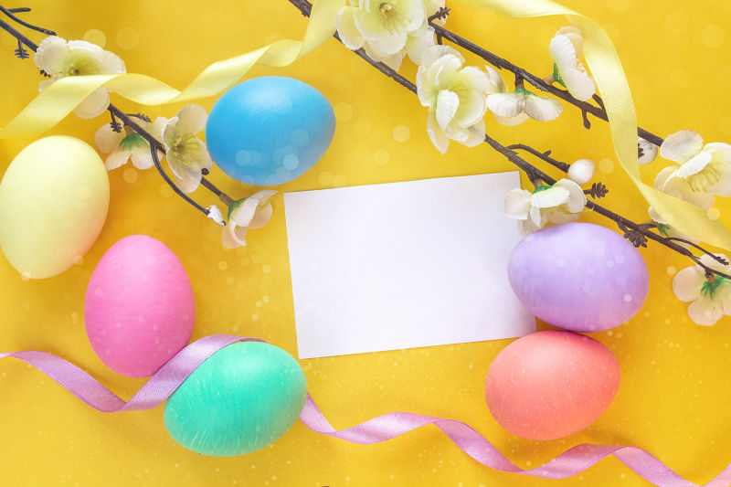 黄色背景下的复活节彩蛋与空白卡纸