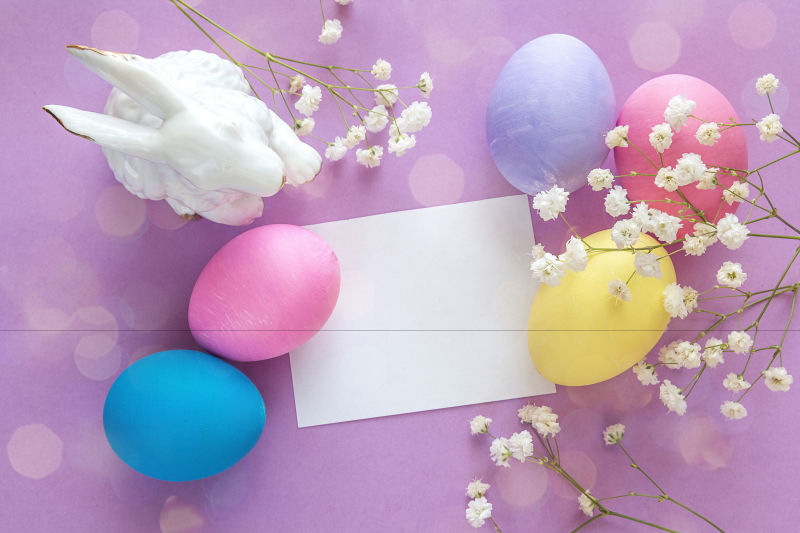 紫色背景下的复活节彩蛋与白色的兔子玩具