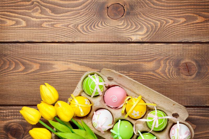 木纹理桌上装好的复活节彩蛋和黄色郁金香