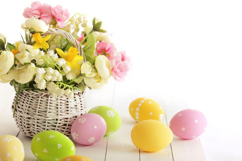 白色背景上的竹篮里的花朵和复活节彩蛋
