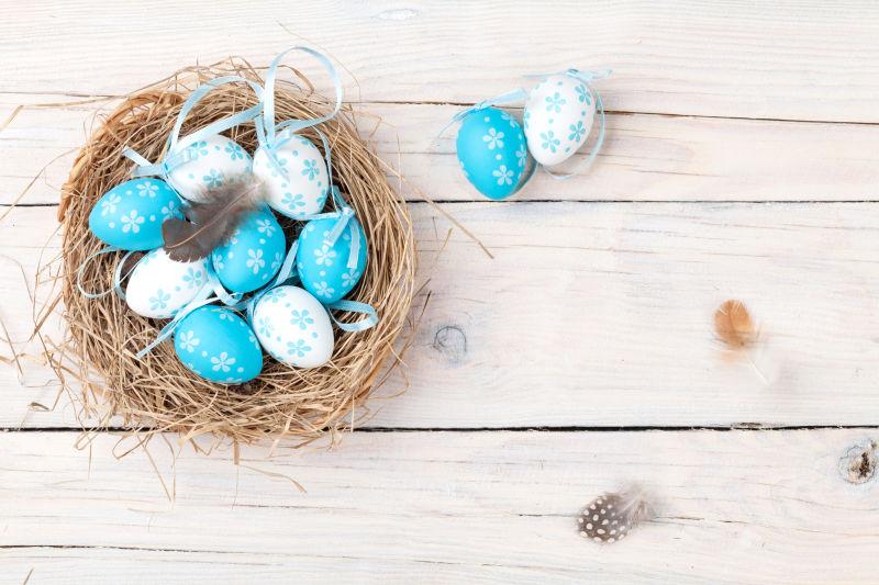 白色木桌上燕窝中蓝色和白色的复活节彩蛋